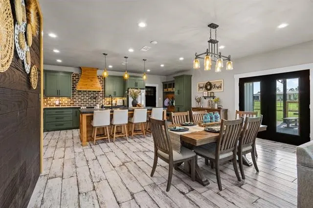 a dining room with stainless steel appliances kitchen island granite countertop a table chairs and a view of kitchen