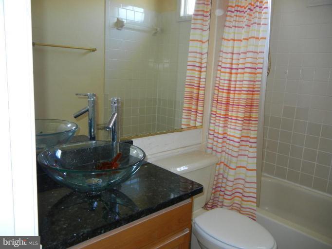 6568 Forsythia Street Springfield, VA 22150 - Photo 15 of 15 a bathroom with a granite countertop sink a toilet and mirror