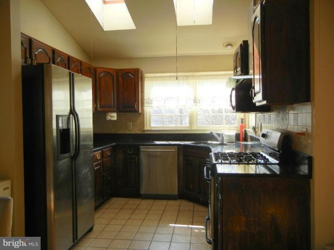 6568 Forsythia Street Springfield, VA 22150 - Photo 7 of 15 a kitchen with stainless steel appliances granite countertop a refrigerator and a stove