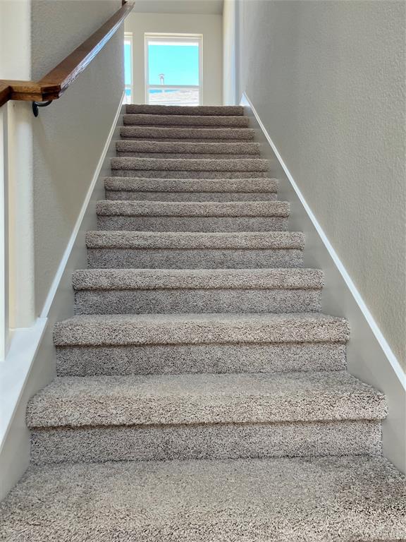 128 Free Stone Drive Georgetown, TX 78628 - Photo 10 of 29 Carpeted staircase featuring a wooden handrail, white trim, and light-toned walls