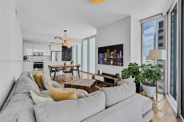 a living room with furniture potted plant and kitchen view