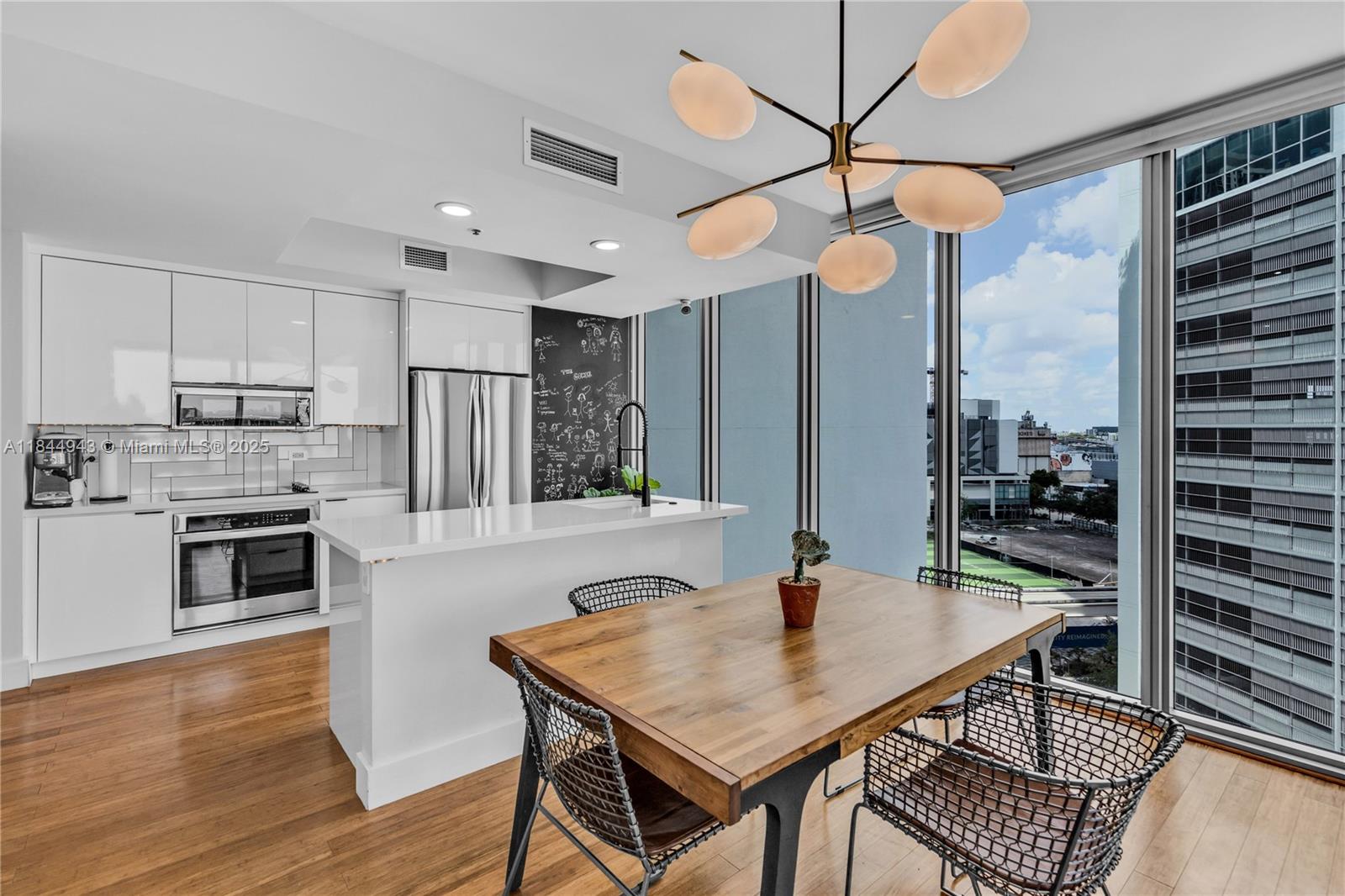 888 Biscayne Boulevard, Unit 812 Miami, FL 33132 - Photo 8 of 36 a kitchen with stainless steel appliances kitchen island granite countertop a stove a sink a dining table and chairs with wooden floor