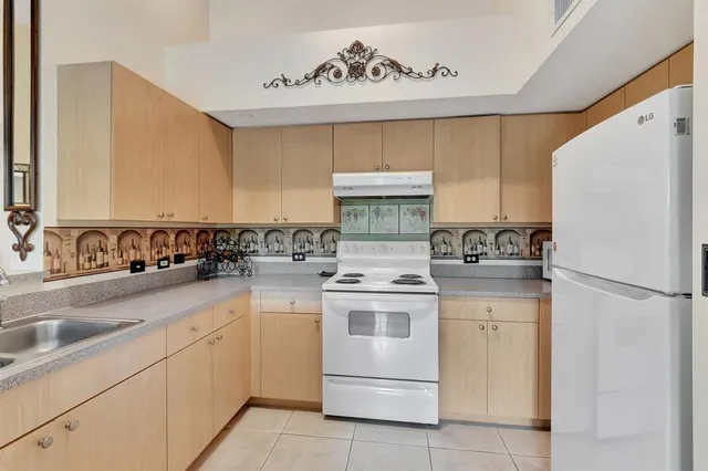 a kitchen with a sink a refrigerator and cabinets