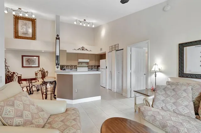 a kitchen with stainless steel appliances kitchen island granite countertop a refrigerator a stove a dining table and chairs with wooden floor