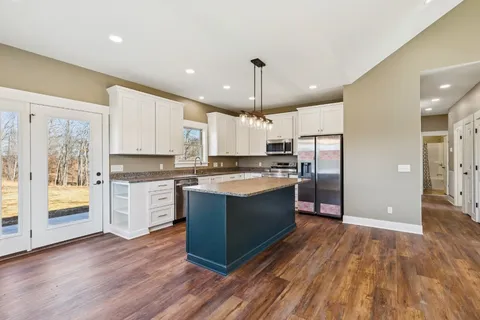 a large kitchen with stainless steel appliances granite countertop wooden cabinets a sink a stove a dining table and chairs