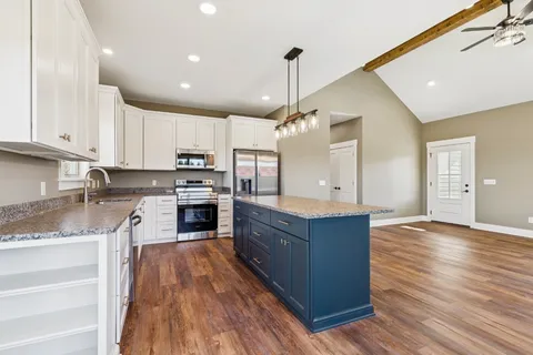 a large kitchen with stainless steel appliances granite countertop a stove and a wooden floors