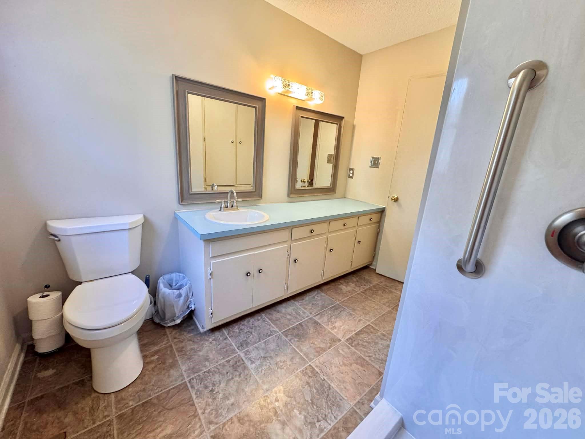 769 Dowd Road Candor, NC 27229 - Photo 15 of 32 a bathroom with a granite countertop toilet a sink and a mirror