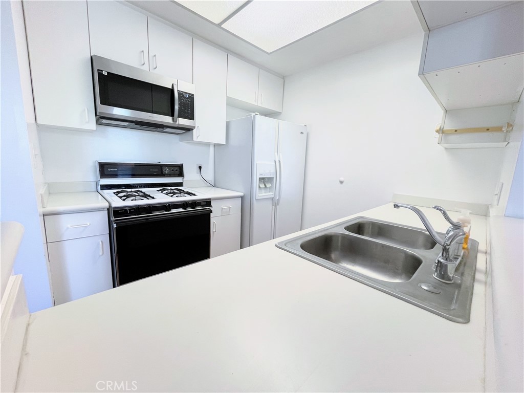 19350 Sherman Way, Unit 137 Reseda, CA 91335 - Photo 4 of 21 a kitchen with a sink a microwave and cabinets
