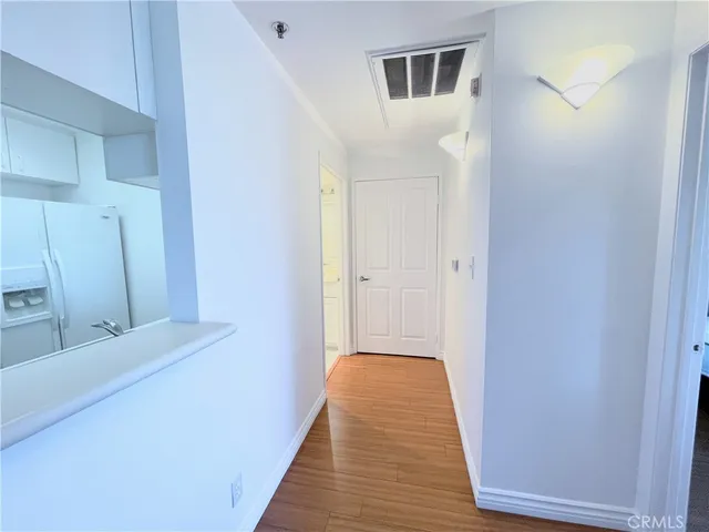 a view of a hallway with wooden floor and a bathroom