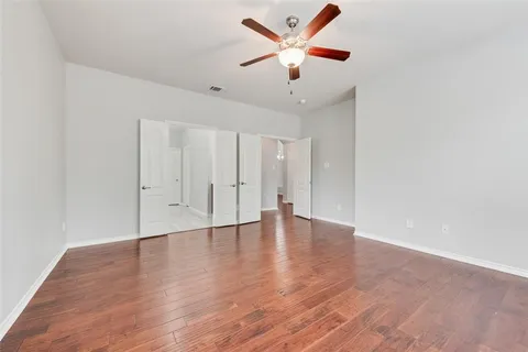 an empty room with wooden floor and a ceiling fan