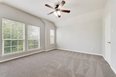 an empty room with chandelier fan and windows