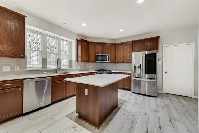 a kitchen with stainless steel appliances granite countertop a stove a sink dishwasher a refrigerator and a microwave oven with wooden floor