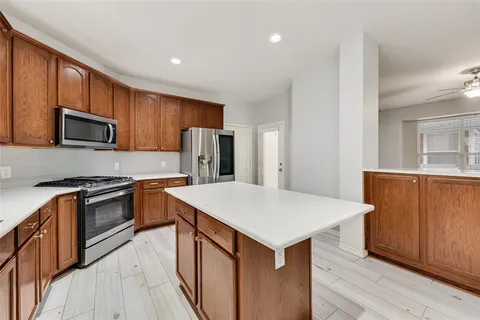 a kitchen with stainless steel appliances a stove top oven a sink dishwasher a refrigerator and a refrigerator with wooden floor