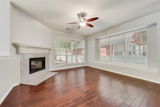 a view of an empty room with wooden floor fireplace and a window