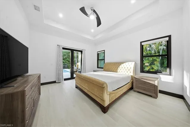 a bedroom with a large bed and a flat tv screen on dresser