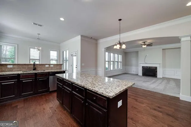 a kitchen with stainless steel appliances granite countertop wooden cabinets a refrigerator a sink a stove a microwave and wooden floors