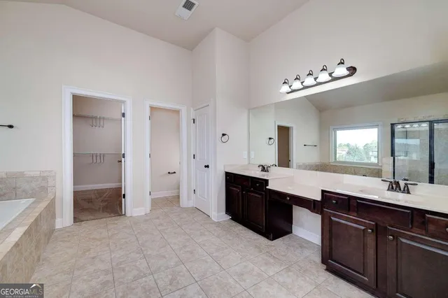 a spacious bathroom with a tub shower and mirror