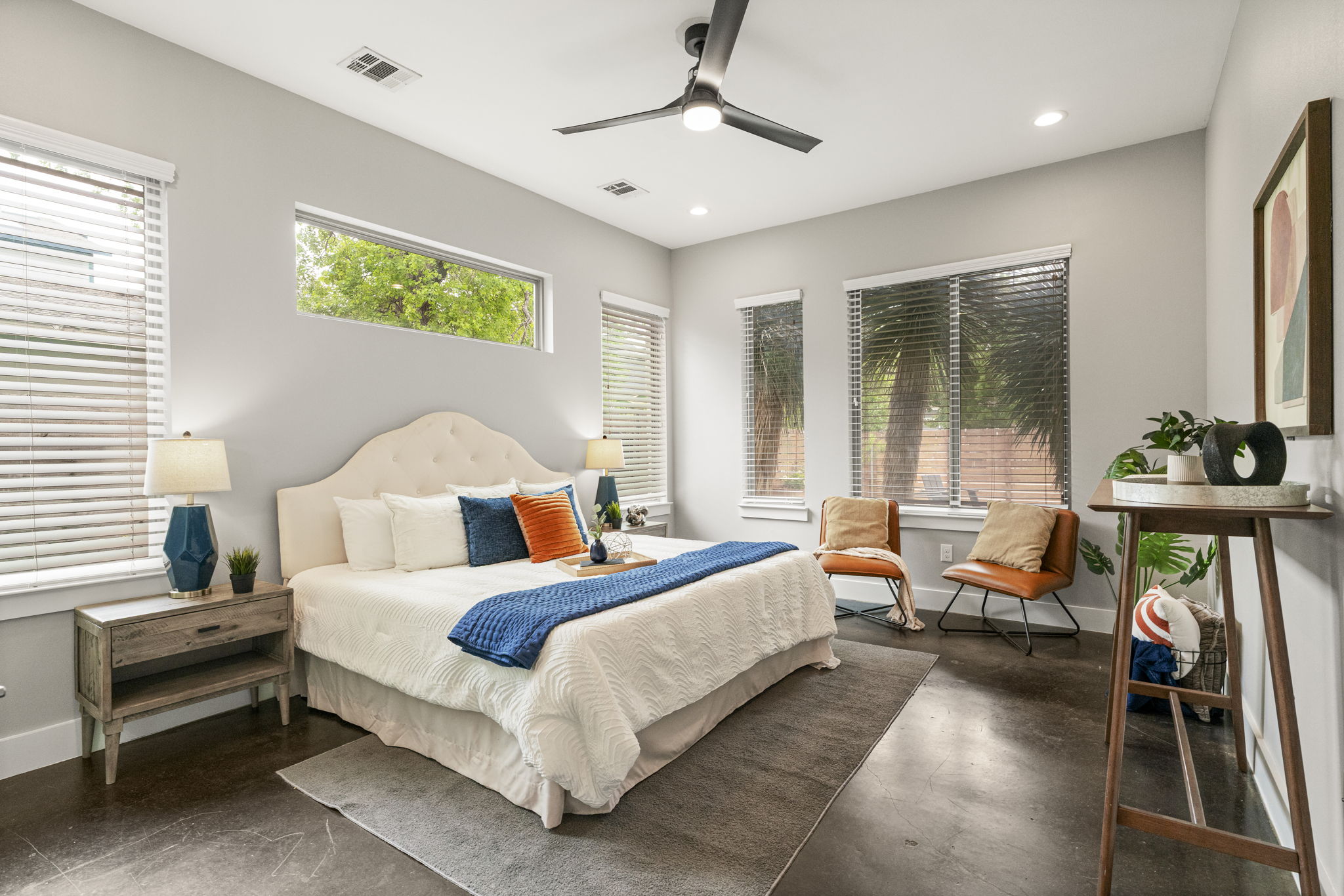 5204 Samuel Huston Avenue Austin, TX 78721 - Photo 21 of 38 Spacious primary bedroom situated downstairs area featuring dark-tone flooring, multiple windows with blinds, a modern ceiling fan, recessed lighting, and light-toned walls