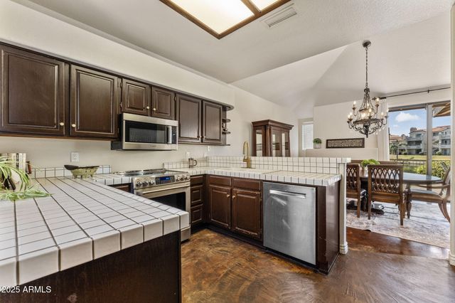 a kitchen with stainless steel appliances granite countertop a stove top oven a sink dishwasher a dining table and chairs with wooden floor