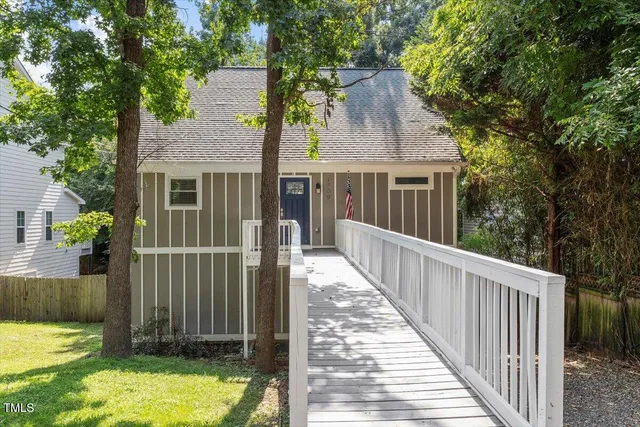 a view of a house with wooden fence next to a yard