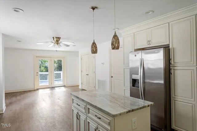 a kitchen with stainless steel appliances granite countertop a refrigerator a sink and white cabinets