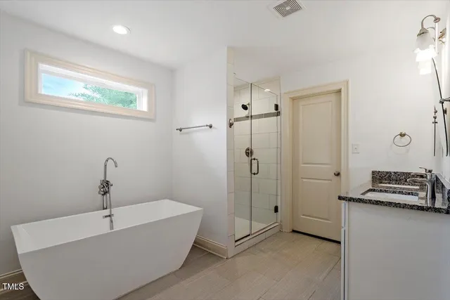 a bathroom with a tub a sink and mirror