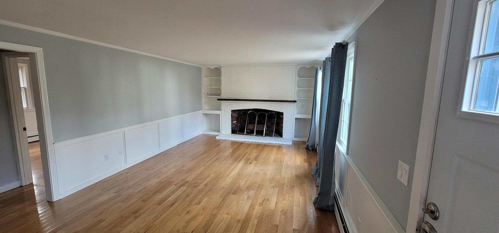 79 Emerson Way Centerville, MA 02632 - Photo 5 of 13 an empty room with wooden floor fireplace and windows