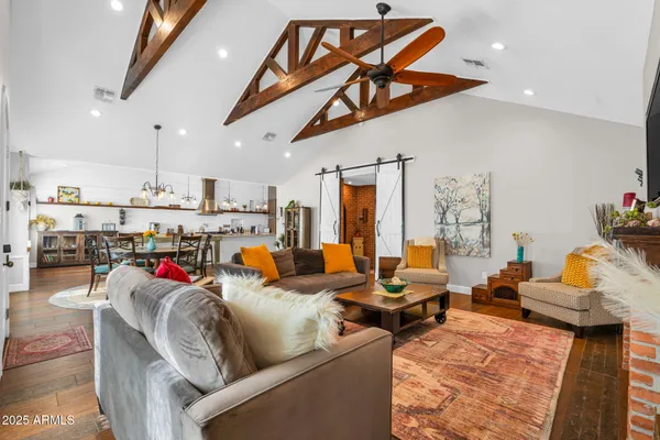 a living room with furniture kitchen view and a wooden floor