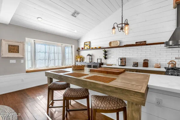 a dining hall with stainless steel appliances granite countertop a dining table and chairs with wooden floor