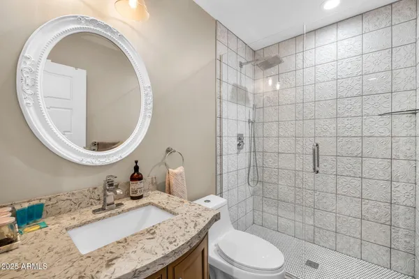 a bathroom with a granite countertop sink a toilet and mirror