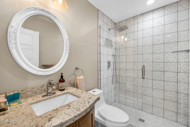 a bathroom with a granite countertop sink a toilet and mirror
