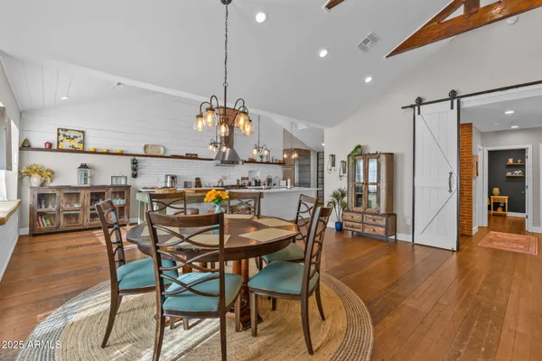 a view of a dining room and livingroom with furniture wooden floor kitchen view and a chandelier