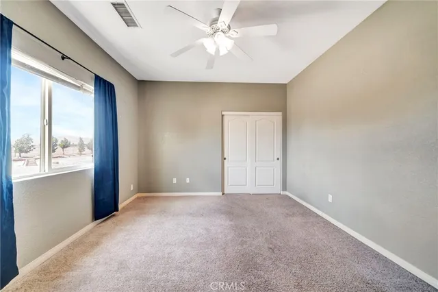an empty room with windows and ceiling fan