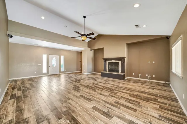 a view of an empty room with window and wooden floor
