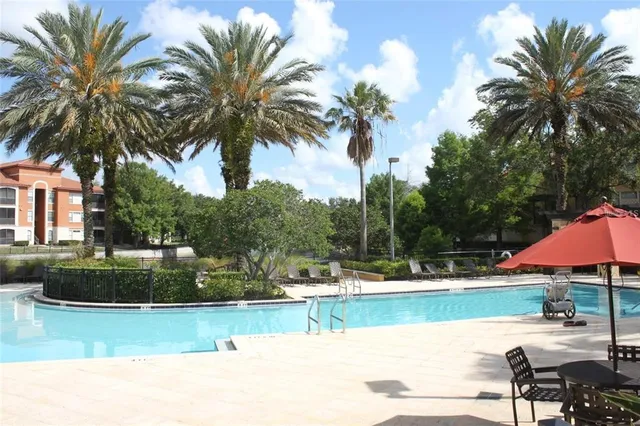 a view of a swimming pool with a table and chairs under an umbrella