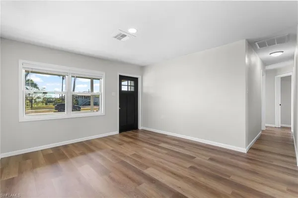 a view of an empty room with wooden floor and a window