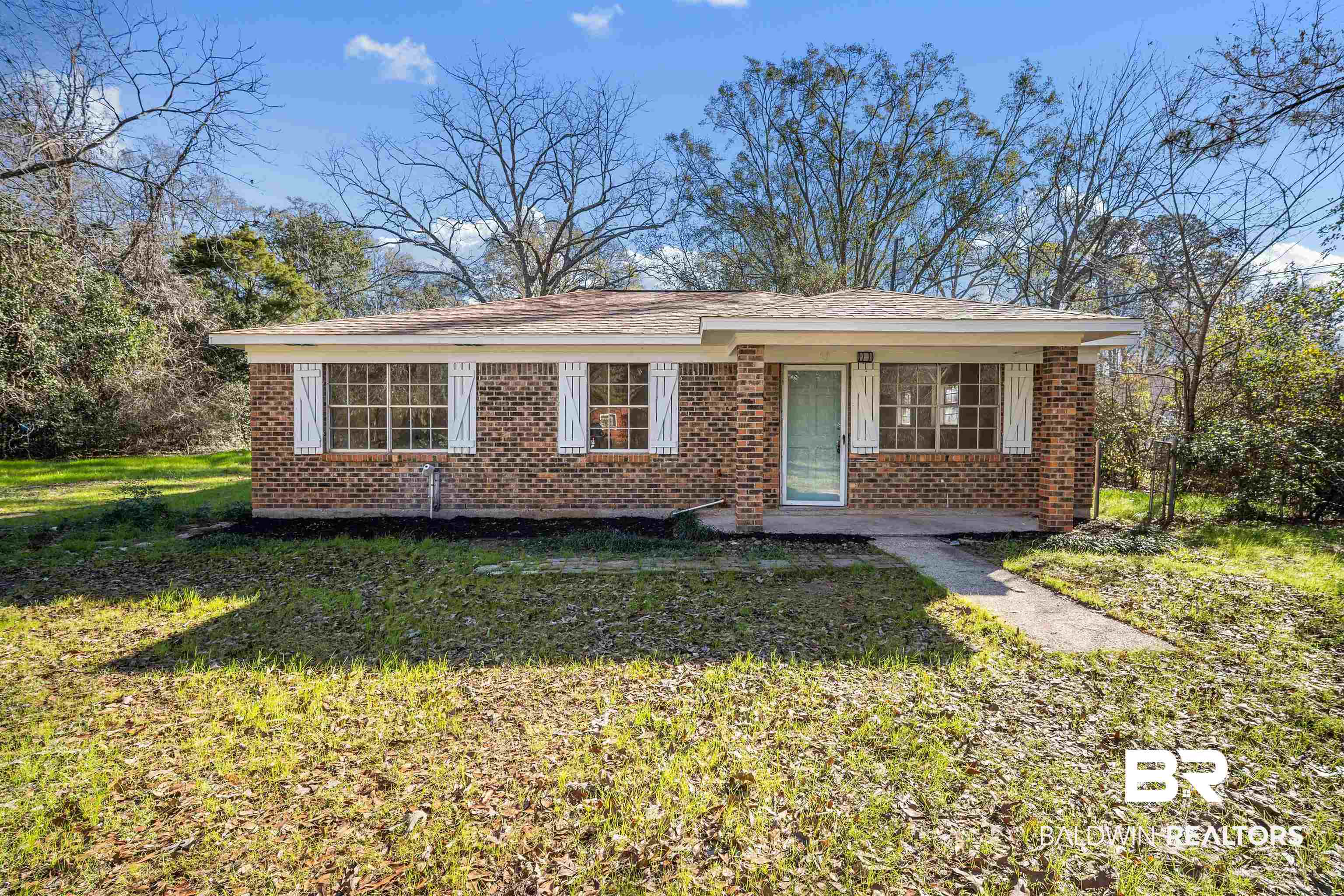 View of front of house with a front lawn, brick siding, and covered porch