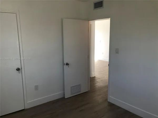 a view of an empty room with wooden floor and closet