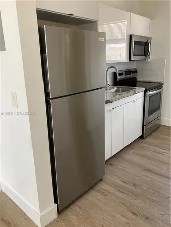 a kitchen with a refrigerator a microwave a sink and cabinets