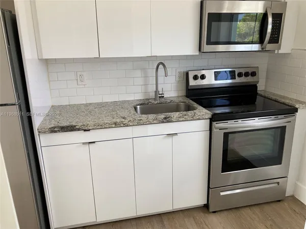 a kitchen with granite countertop white cabinets and white appliances