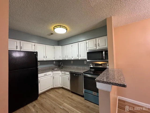 a kitchen with granite countertop a refrigerator stove top oven and sink