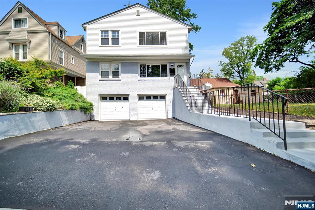 a view of a white house with large tree and wooden fence