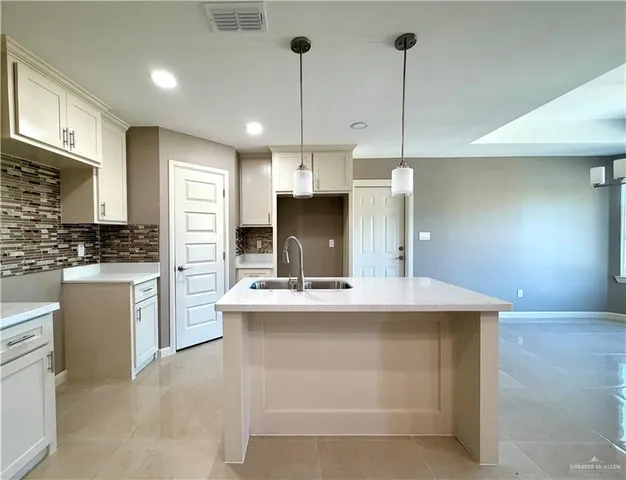 a kitchen with kitchen island a counter top space a sink stainless steel appliances and cabinets