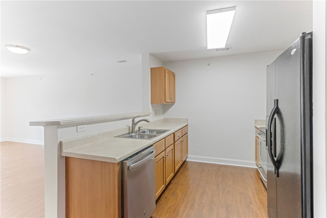Warm wood cabinetry and durable hard-surface flooring frame this functional kitchen space.