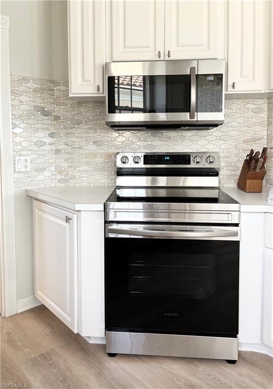 5477 Freeport Lane Naples, FL 34119 - Photo 11 of 36 a kitchen with stainless steel appliances granite countertop white cabinets and a stove top oven