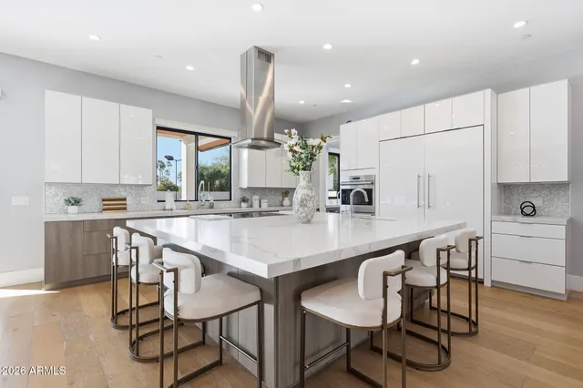 a kitchen with kitchen island a dining table chairs cabinets and wooden floor
