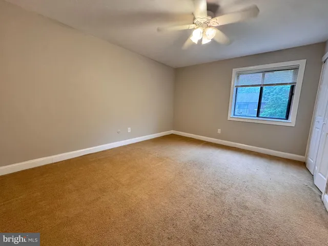 an empty room with a window and a ceiling fan