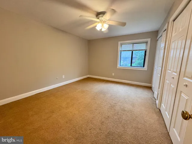 an empty room with windows and fan