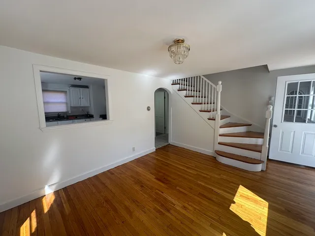 a view of an empty room with wooden floor and stairs