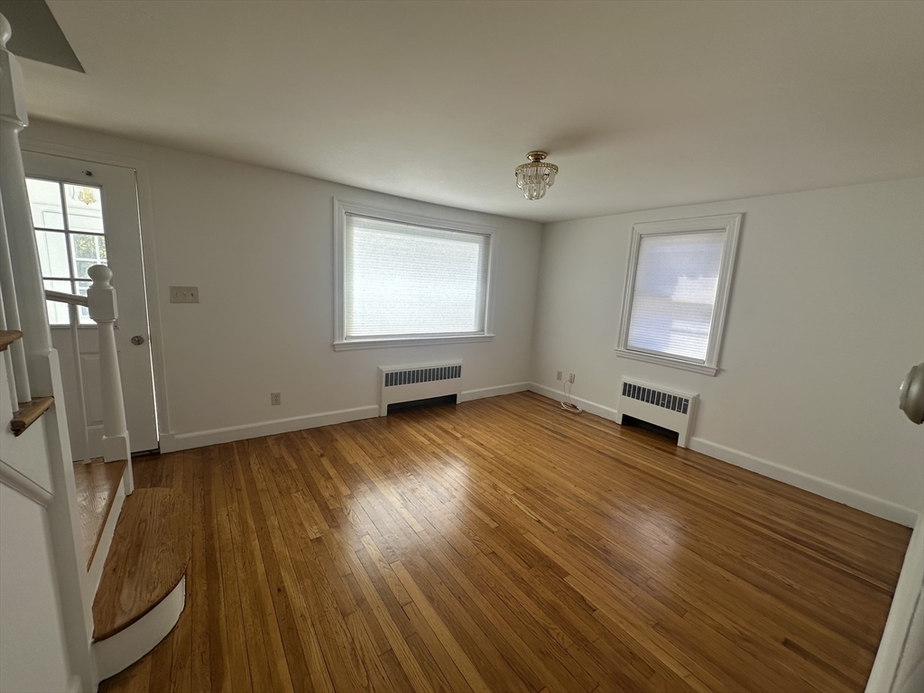 206 Adams Street, Unit 206 Newton, MA 02458 - Photo 2 of 37 an empty room with wooden floor and windows